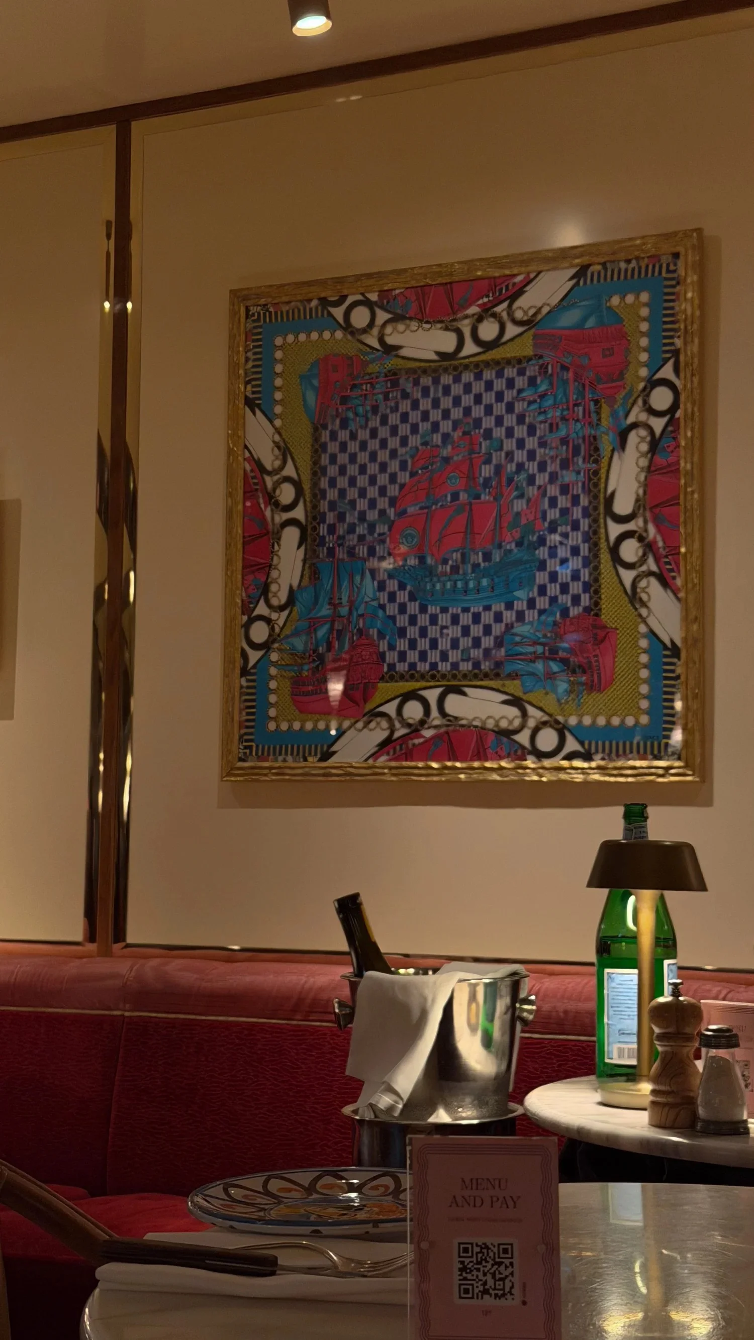 Colourful framed artwork above a red restaurant booth.