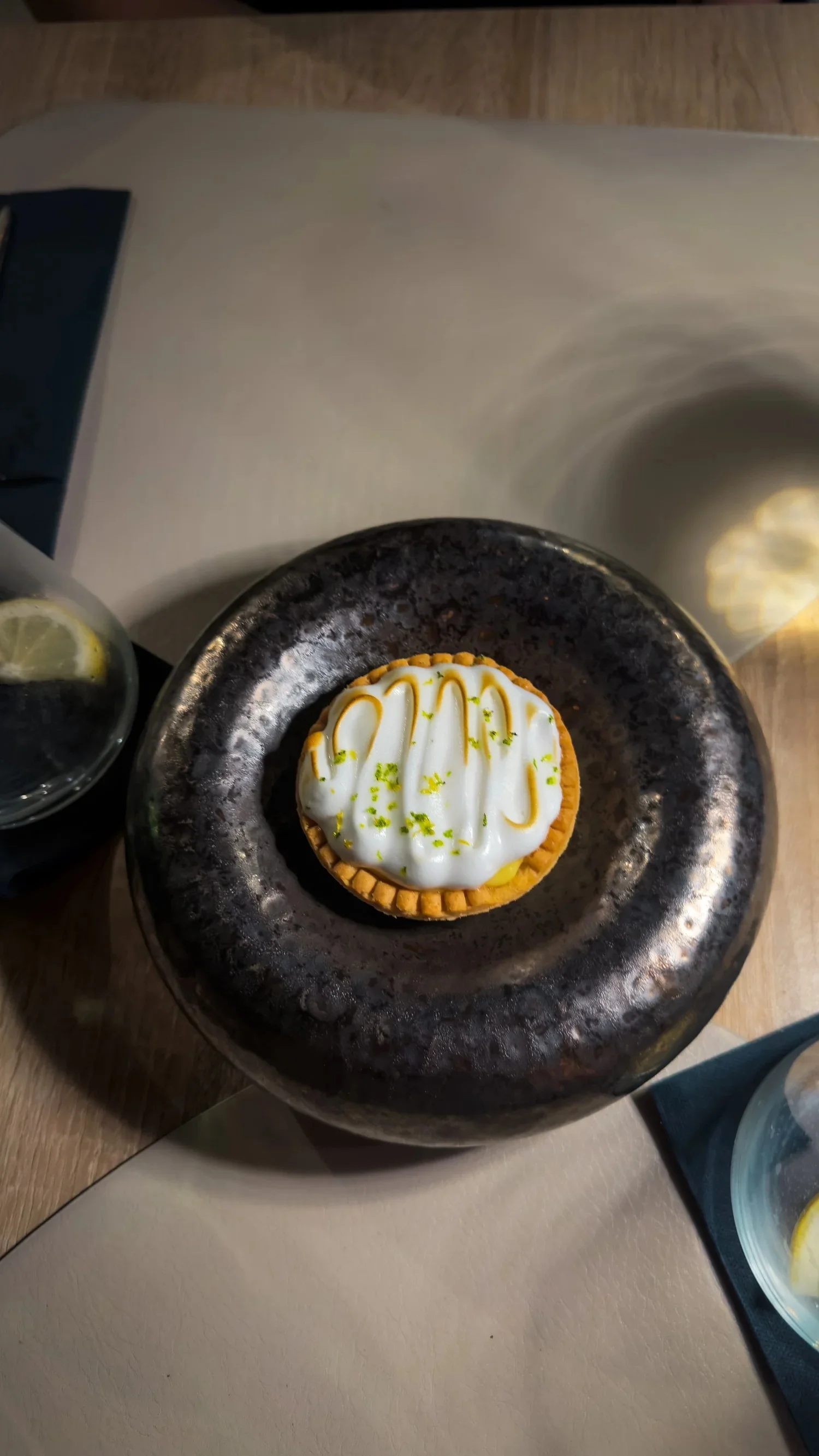 Lemon meringue tart served on a dark plate at Restaurant Arka