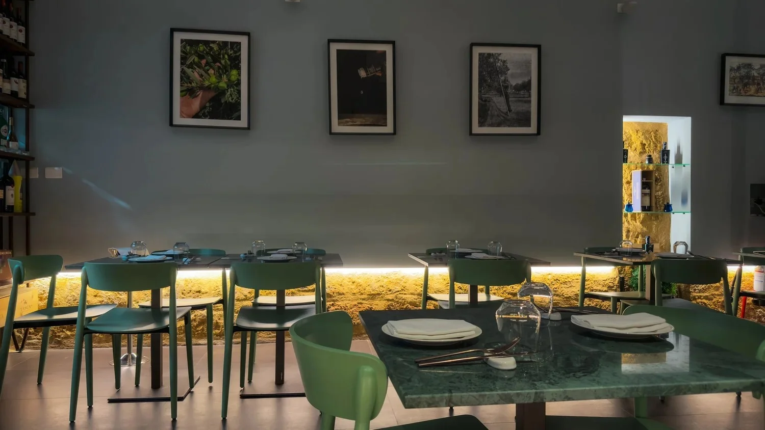 Restaurant dining room with green stone tables, green chairs and framed photographs.