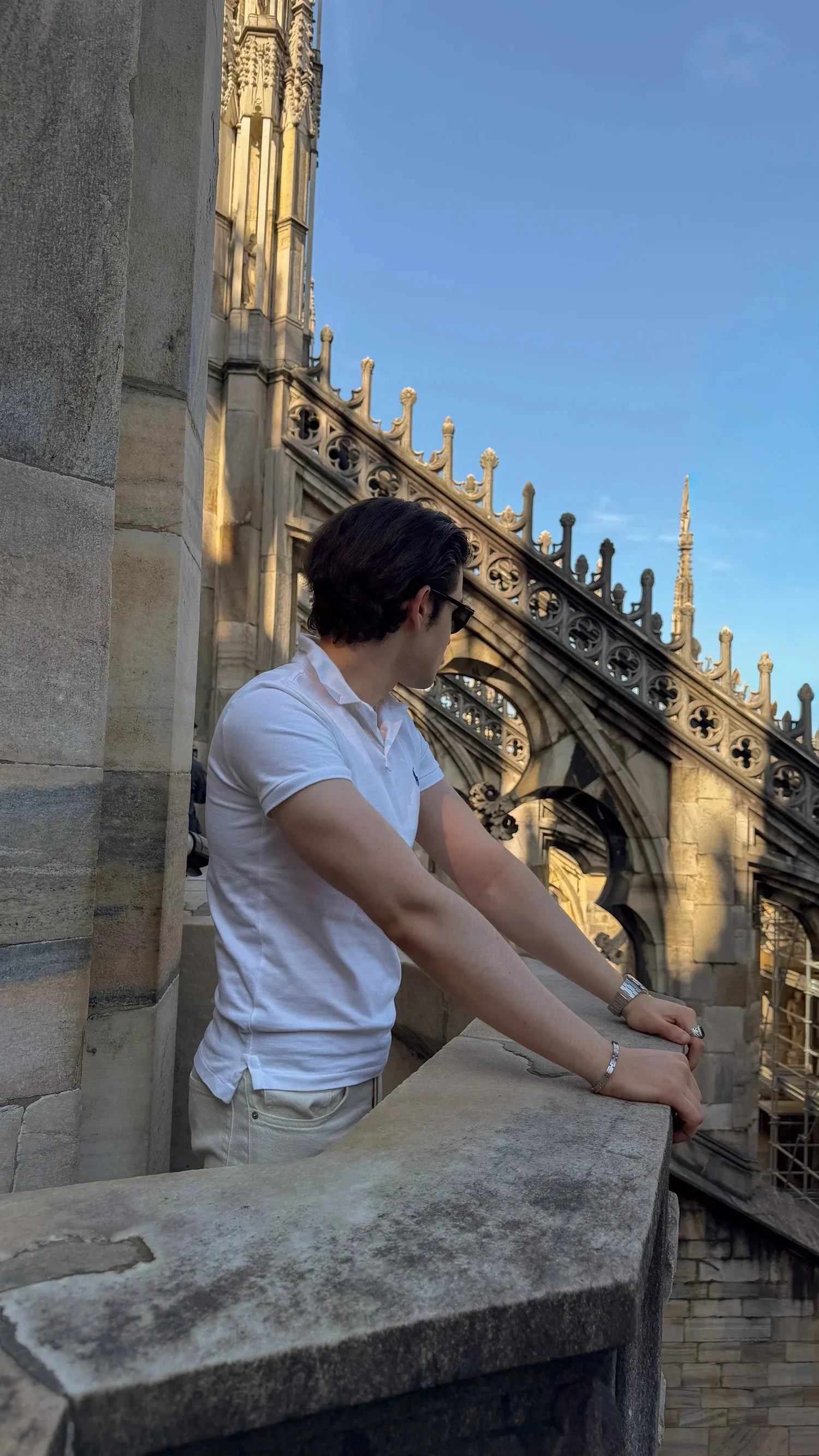 A person looking out from a stone terrace on Milan Cathedral.