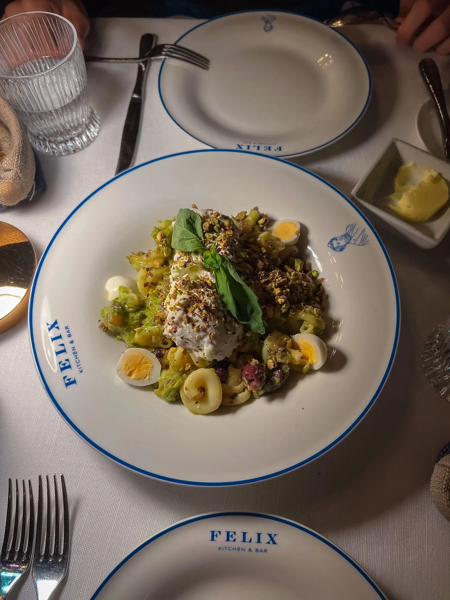 A pasta dish with greens and grated garnish on a FELIX plate.