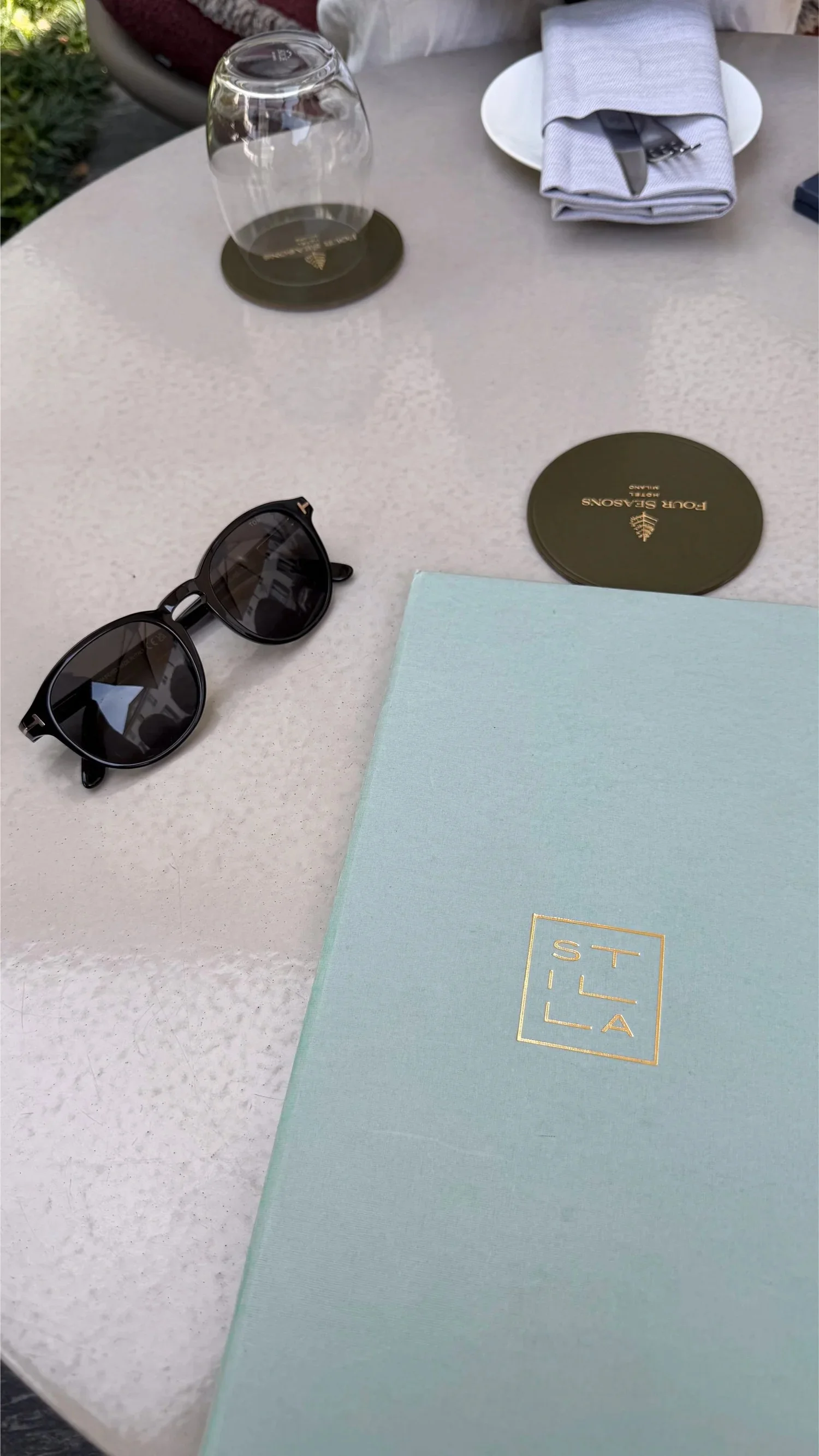 Sunglasses and a pale blue menu beside a place setting.