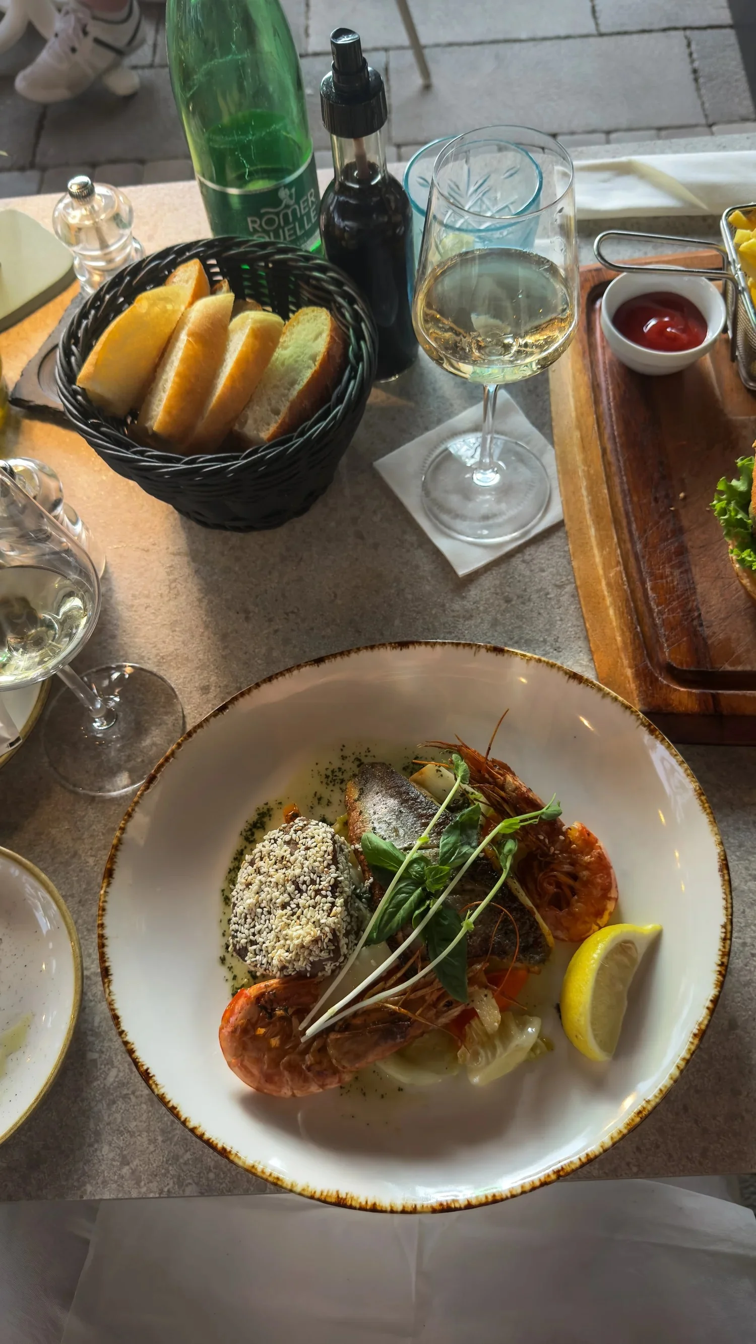 A plated fish course with side dishes and wine at Restaurant La Bohème in Cavtat.