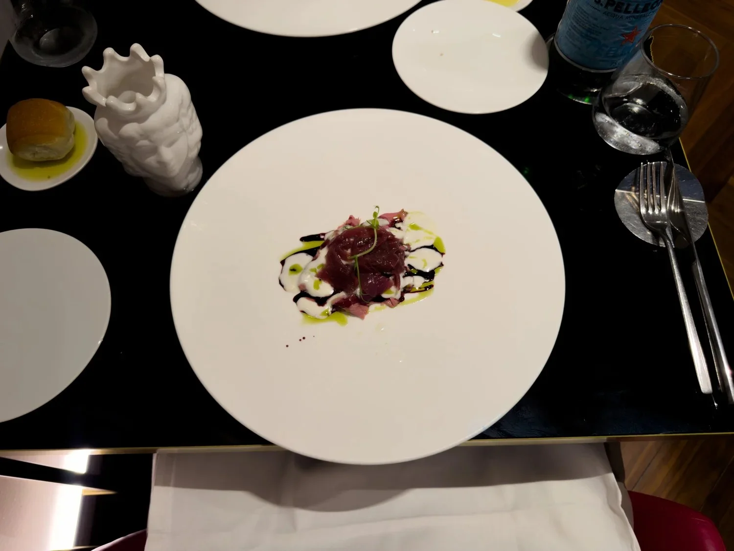 A small plated starter with dark red garnish and green sauce.
