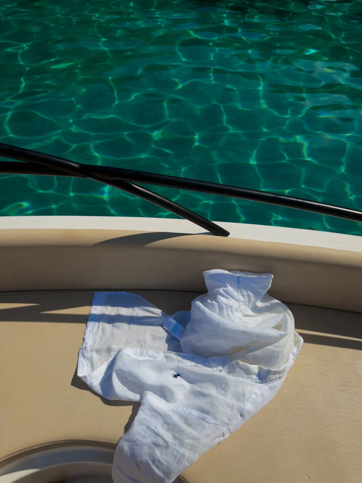 White towels on a boat seat above clear turquoise water.