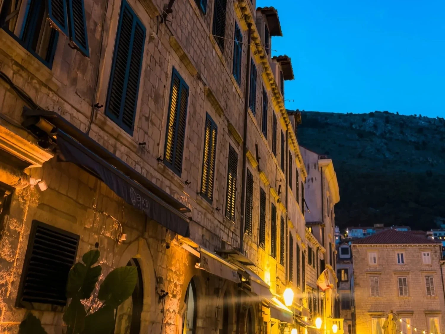 Historic stone buildings lit warmly along a street at dusk.