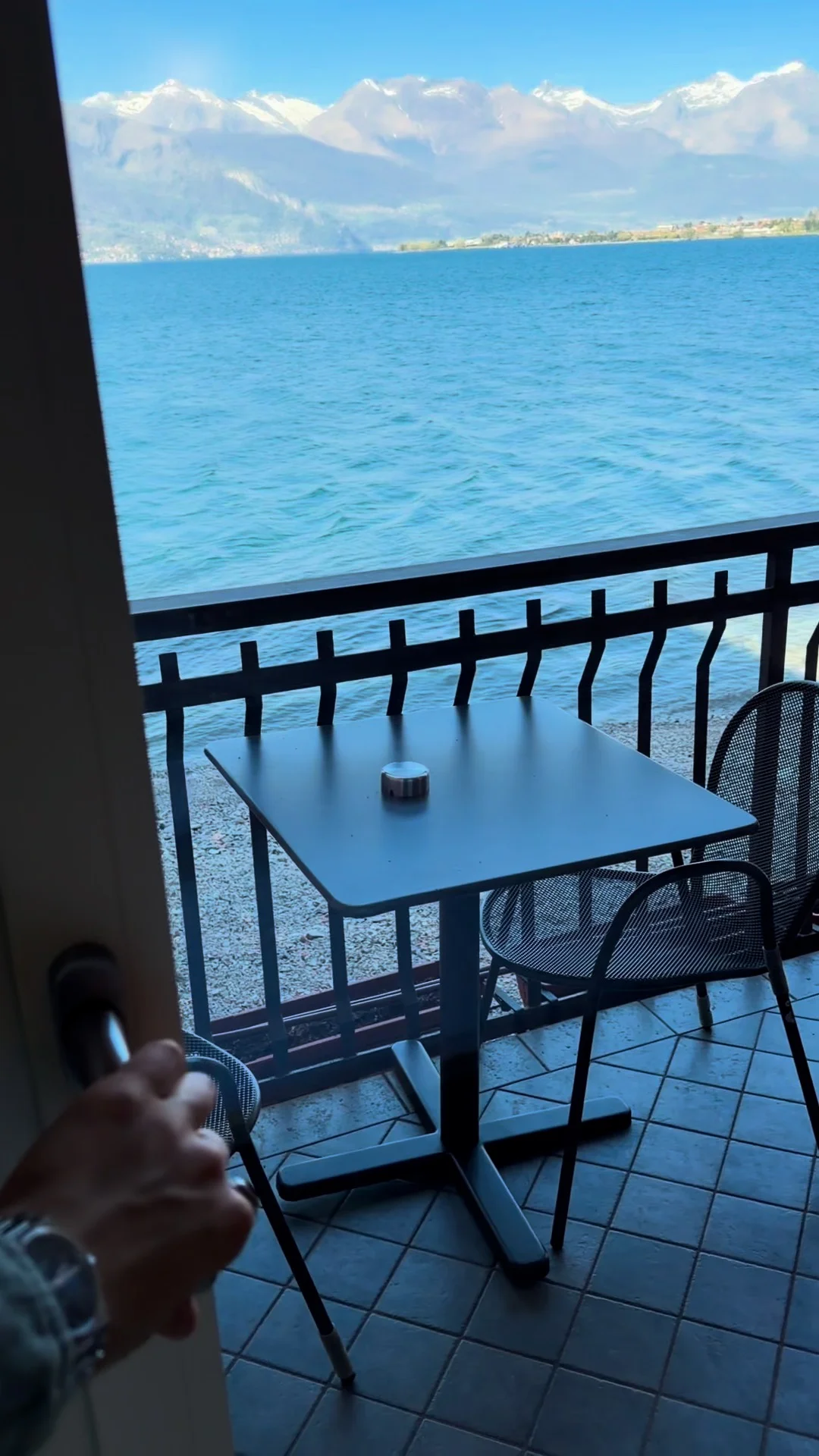 A small balcony table overlooking blue lake water.