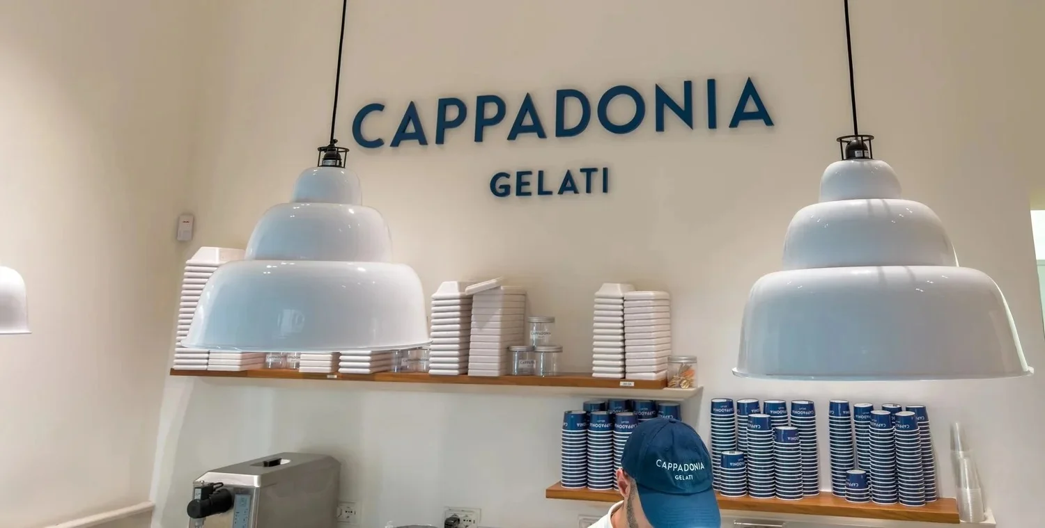 Cappadonia Gelati counter with white pendant lights and blue lettering.