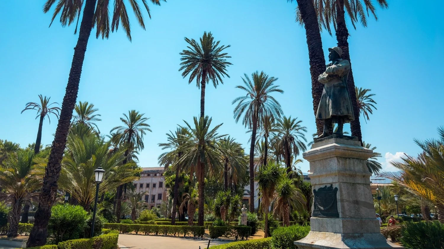 Bronze monument to Gaetano Bucceri surrounded by palm trees and gardens at Villa Bonanno in Palermo.