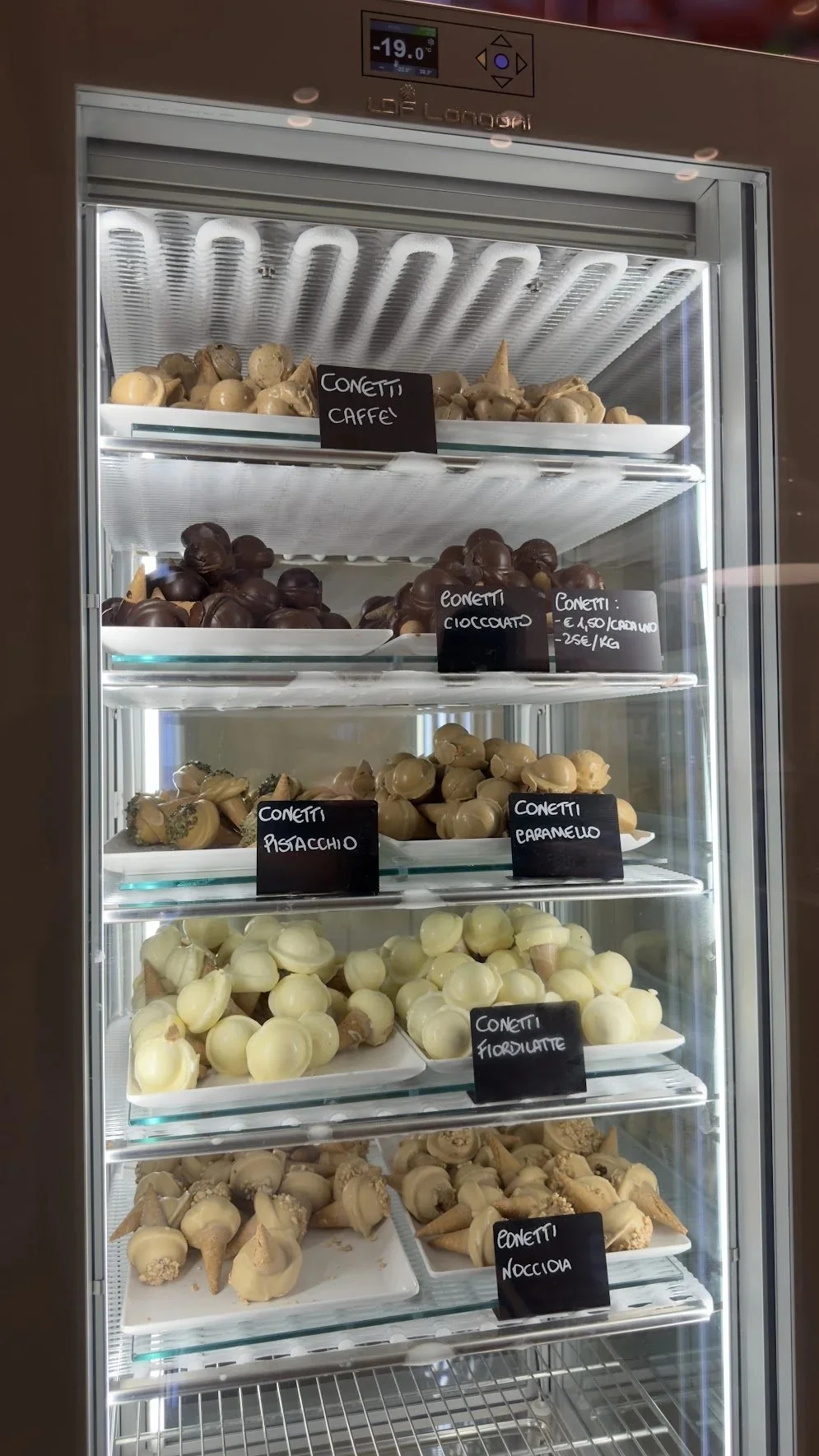 A refrigerated display filled with rows of small desserts.
