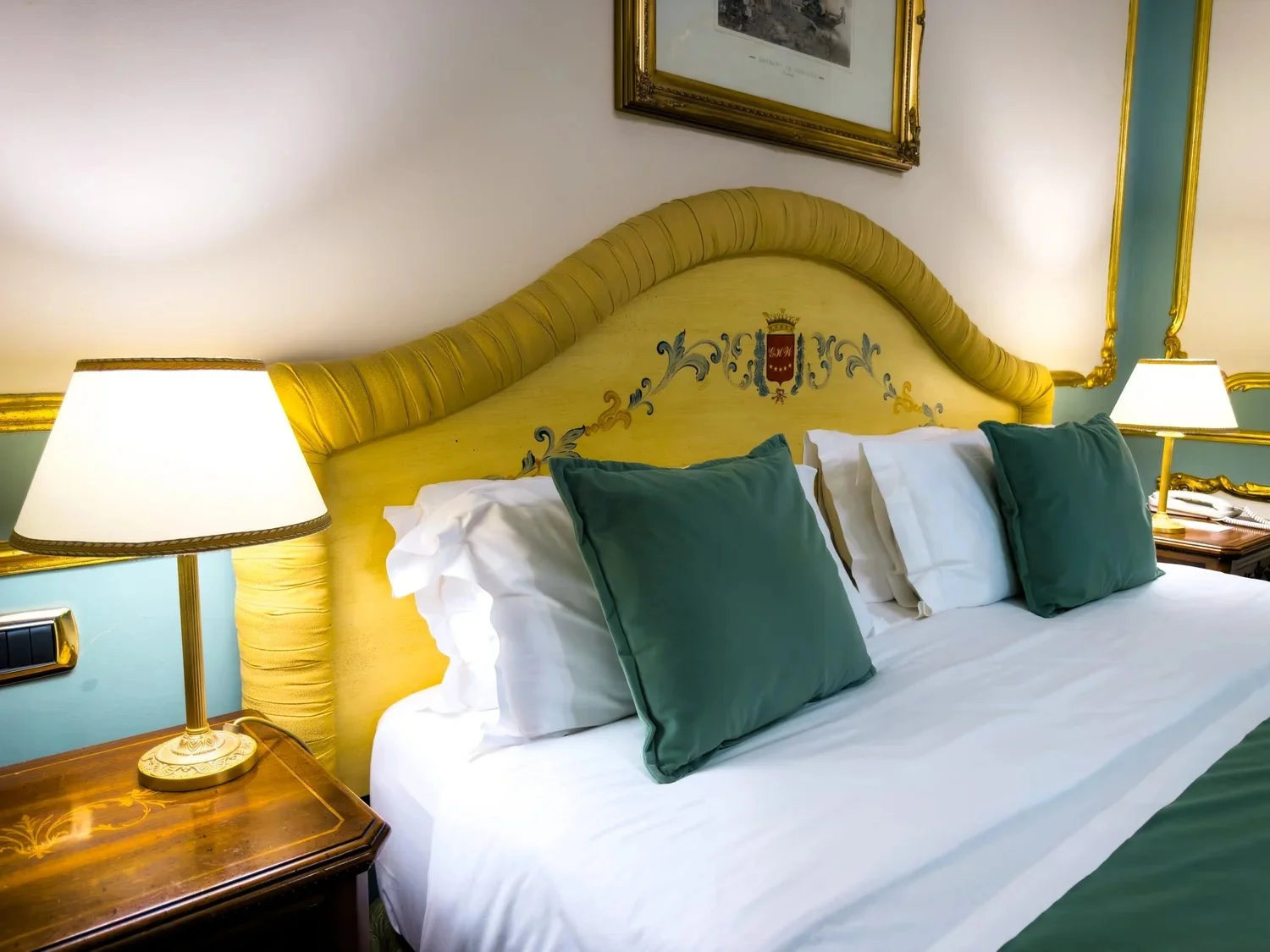 White pillows and green cushions against a yellow upholstered headboard.