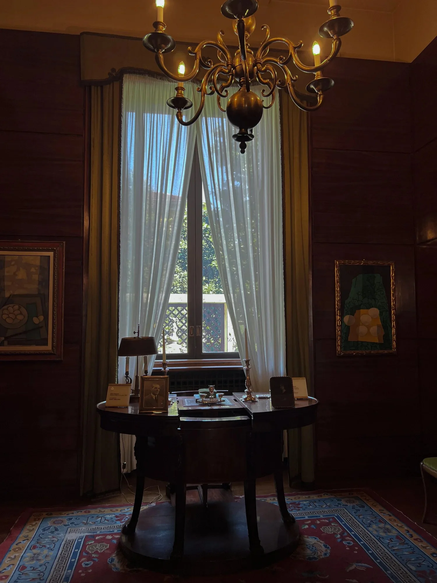 An elegant room with a chandelier, tall curtains and a wooden table.