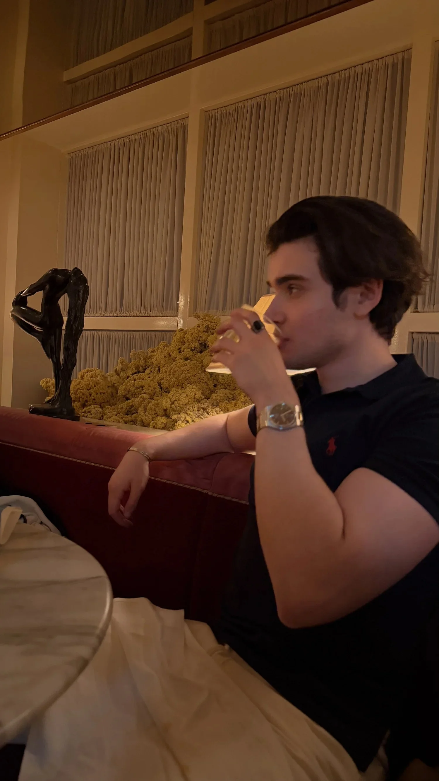 A person drinking from a glass while seated in a restaurant booth.