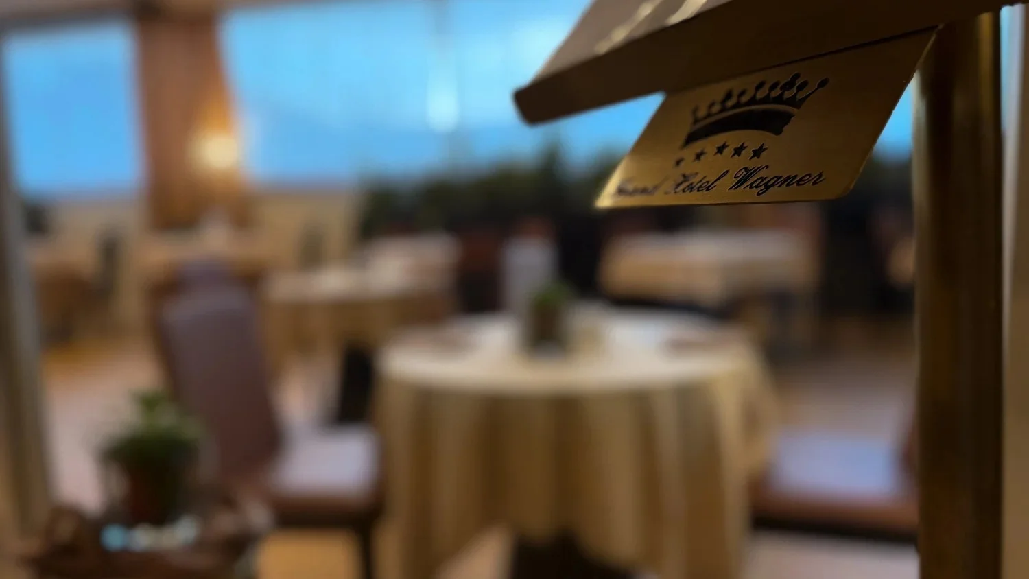 A hotel dining-room sign beside a doorway overlooking round tables.