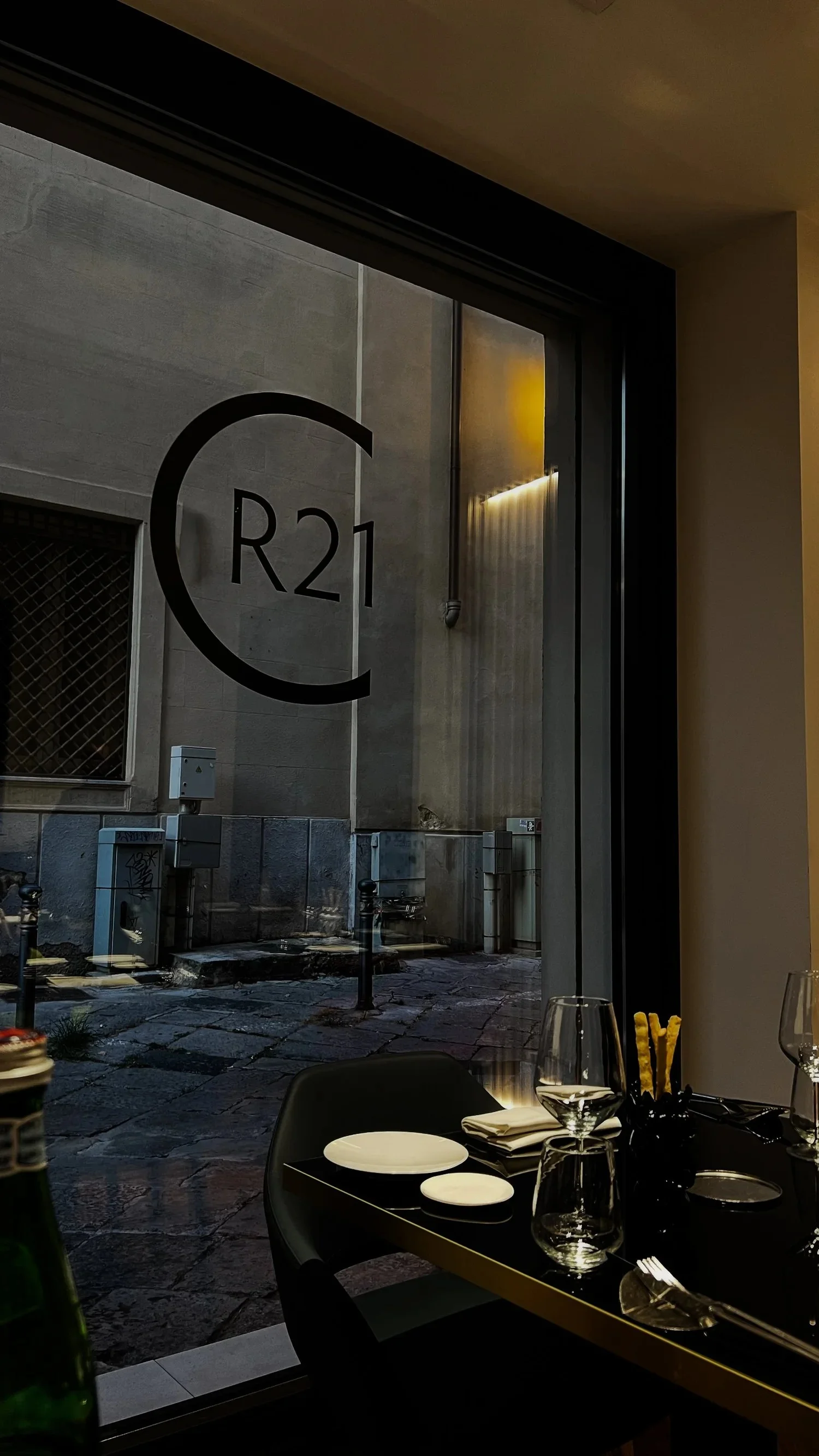 CR21 lettering on a restaurant window beside a set dining table.